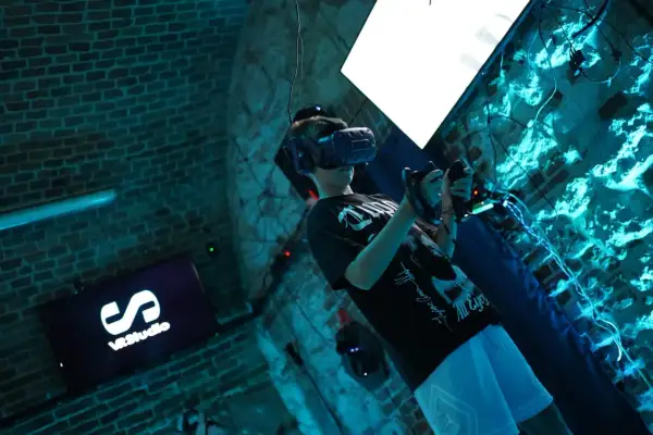 Chłopak w goglach VR w Krakowie, zanurzony w wirtualnej rzeczywistości. Na ekranie logo VRStudio.