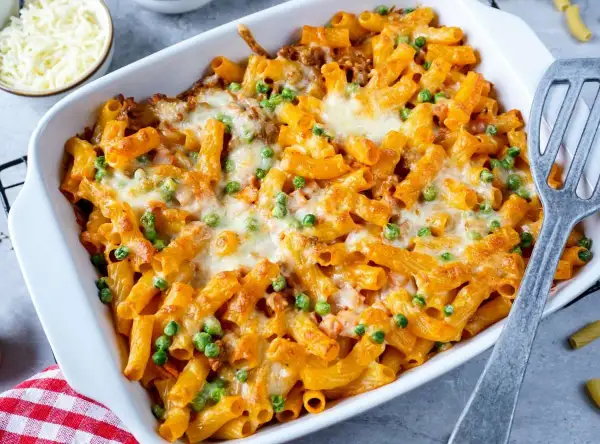 Herzhaftes Rigatoni al Forno mit Erbsen und geschmolzenem Käse in einer Auflaufform, bereit zum Servieren.