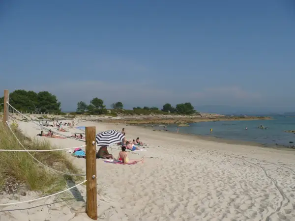 Gente disfrutando del sol en unas tranquilas playas nudistas Galicia, con arena dorada y aguas cristalinas.