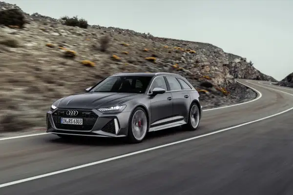 Audi RS6 Avant gris en movimiento en una carretera sinuosa, demostrando su velocidad máxima en un paisaje montañoso.