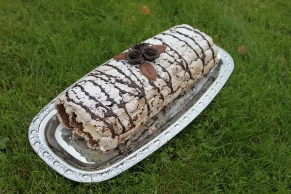 En läcker Budapestrulle med chokladrosor och pudersocker, redo att avnjutas. Ett perfekt recept för fika.