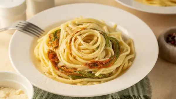 Un piatto di spaghetti conditi con delicati fiori di zucca, un classico della cucina italiana.