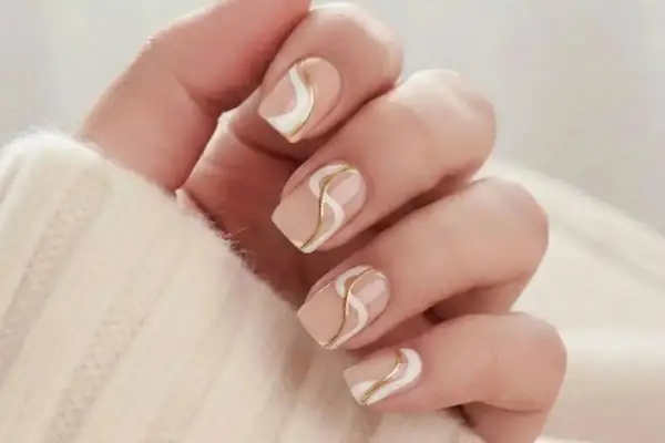 Nagel inspi: Nudefärgade naglar med eleganta vita och guldfärgade vågmönster.