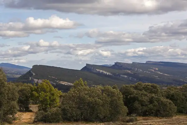Paisaje montañoso con formaciones rocosas afiladas, típico de fotos de ojo Guareña. Nubes blancas y cielo azul.