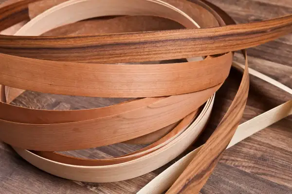 Nastri di impiallacciatura in legno di diverse tonalità, con un effetto plastica che ne esalta la texture naturale.