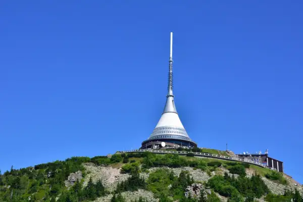 Wieża telewizyjna na górze Ještěd, jedna z głównych libereckich atrakcji, góruje nad zielonymi wzgórzami.