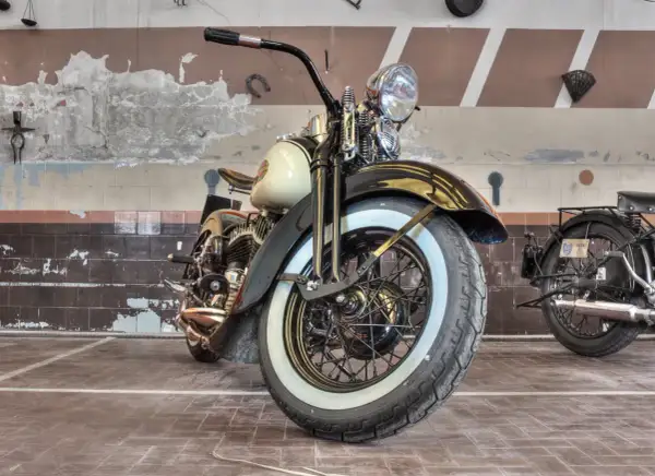 Klasyczny motocykl z białymi bokami opon, stojący w garażu.