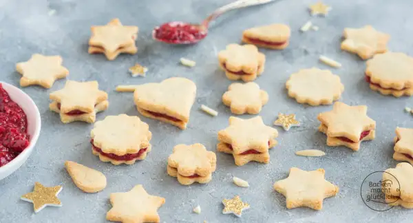 Sterne und Herzen aus veganen Keksen mit Marmeladenfüllung, dekoriert mit glitzernden Sternen.