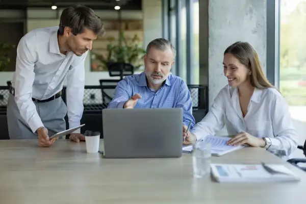 Professionisti discutono su come tutelarsi per affittare un negozio, analizzando contratti al computer.
