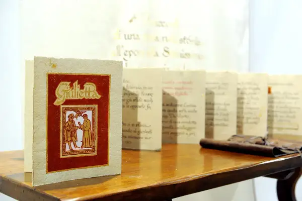 Libri con copertina rossa e dorata, "Giulietta", e altri volumi con testo calligrafico, esempi di prodotti artigianali Friuli Venezia Giulia.
