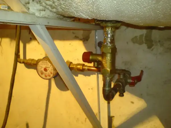 Zawór bezpieczeństwa w bojlerze, obok wodomierza, zapewnia ochronę instalacji.