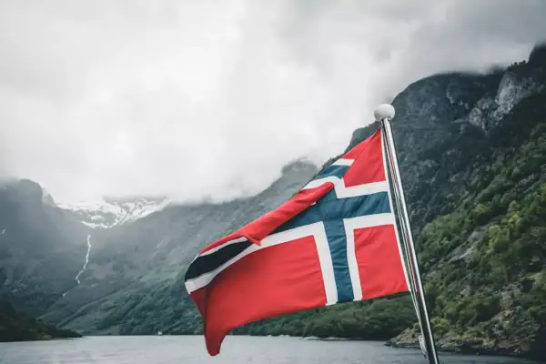 Norwegia: malownicze fiordy i wysokie norwegia zarobki netto. Flaga powiewa na maszcie, zapraszając do odkrywania piękna i możliwości.