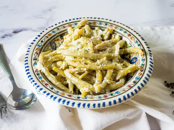 Ein cremiger Bohnensalat mit Sahne, serviert in einer bunten Schüssel. Ein leckeres Gericht, das zum Genießen einlädt.