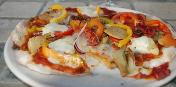 En pizza med surdegsbotten, toppad med mozzarella, paprika, tomat, rödlök och kronärtskocka.