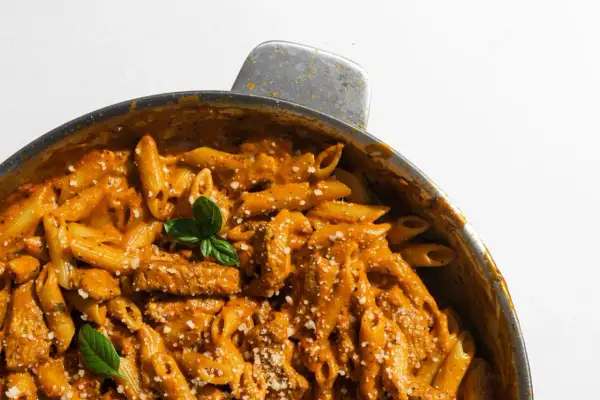 En krämig pasta i ugn med kyckling och en smakrik tomatsås, toppad med färsk basilika och parmesan.