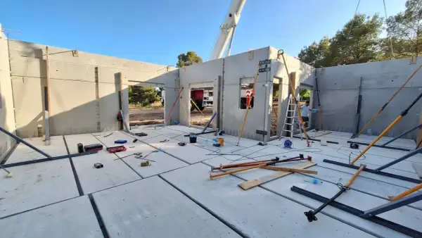 Construcción de una casa prefabricada en Madrid. Se ven paneles de hormigón, puntales y herramientas.