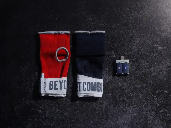 Red and navy hand wraps with "BE YOUR BEST COMBAT" text, and a USB sensor for a boxing match train.