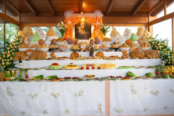 Un'abbondante tavolata ricca di dolci, pani e frutta, che celebra le tradizioni italiane con un'esposizione che ricorda un altare votivo.