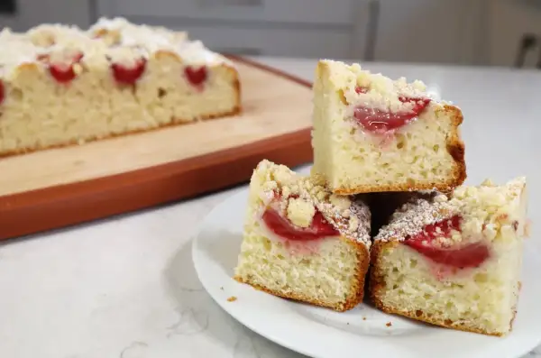 Pyszne ciasto jogurtowe z truskawkami, posypane kruszonką i cukrem pudrem. Idealne na deser!