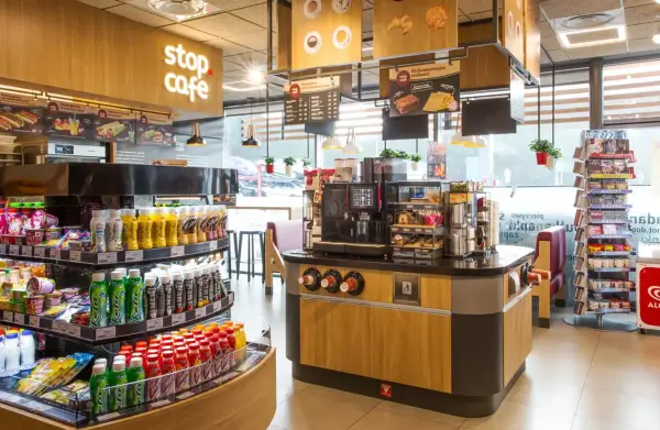 Wnętrze kawiarni Stop Cafe z ladą, ekspresem do kawy, półkami z napojami i przekąskami.