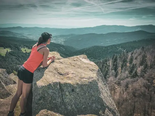 Une randonneuse admire le paysage depuis un rocher. Une parfaite destination randonnée pour s'évader.