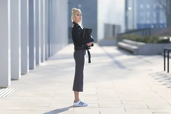 Elegancka kobieta w skórzanej kurtce i ołówkowej spódnicy, prezentująca stylowe adidas superstar stylizacje.
