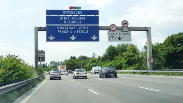 Sur l'autoroute A35, des panneaux indiquent Offenburg, Mulhouse et la Porte Blanche. Des voitures circulent par une journée nuageuse.