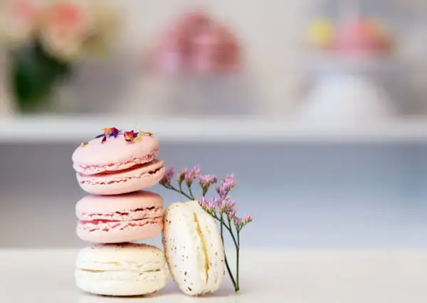En stapel rosa och vita macarons, dekorerade med blommor. Perfekt för ett macarons recept.