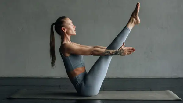 Mujer en postura de equilibrio, practicando yogalates que es una fusión de yoga y pilates para fortalecer el core.