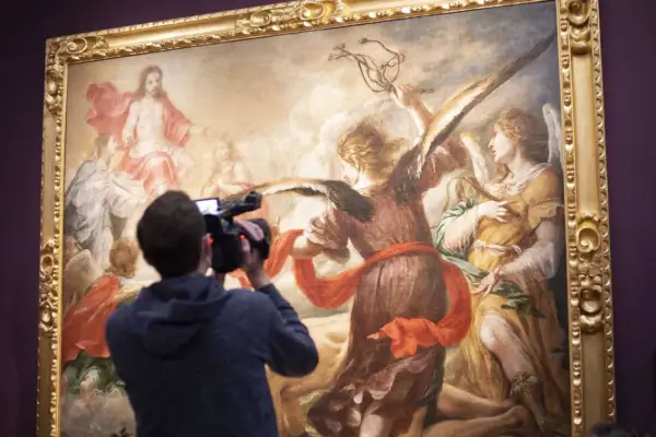Un hombre graba con una cámara una obra de Juan de Valdés Leal, que representa a ángeles y a Jesucristo en el cielo.