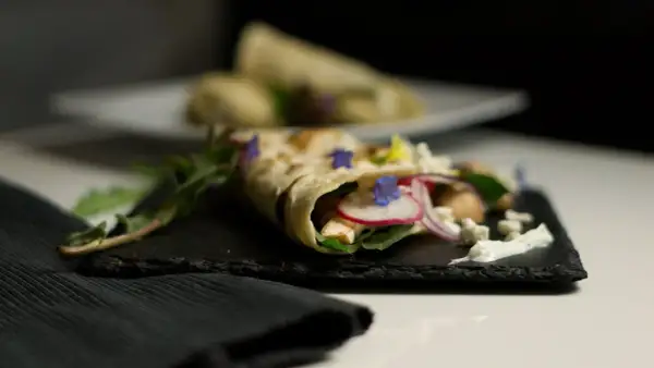 Ein gefüllter Wrap, der zeigt, was sind Tortillas: dünne Fladenbrote, gefüllt mit Hühnchen, Radieschen, Zwiebeln, Käse und Kräutern.