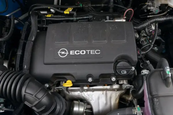 Silnik Ecotec w Oplu Mokka 2024. Widoczny czarny plastikowy dekiel z logo Opla i napisem Ecotec, a także elementy układu dolotowego i chłodzenia.