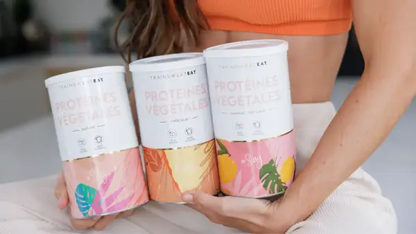 Trois boîtes de protéines végétales "Trainsweat Eat" aux saveurs Nature, Chocolat et Mangue Tropicale. Idéal pour savoir combien de protéine par jour consommer.