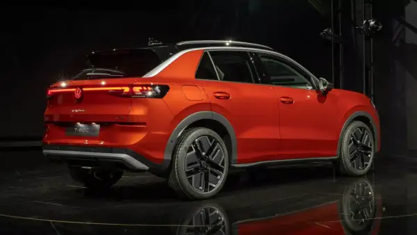 Pomarańczowy Volkswagen T-Roc z czarnym dachem, stylowymi felgami i nowoczesnymi światłami. Sprawdź aktualną volkswagen t-roc cena.