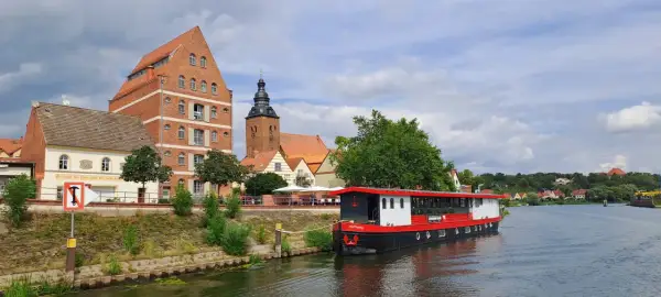 Statek "Hoffnung" cumuje przy brzegu rzeki Łaby w Niemczech, obok zabytkowych budynków i kościoła.