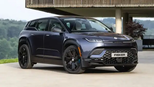 Fisker Ocean, un SUV eléctrico azul oscuro, aparcado frente a una casa moderna con vistas a un bosque.