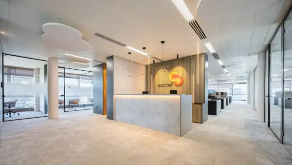 Recepción moderna con logo de "soldef" y mobiliario elegante. El diseño busca crear un ambiente de trabajo que inspire y funcione bien.