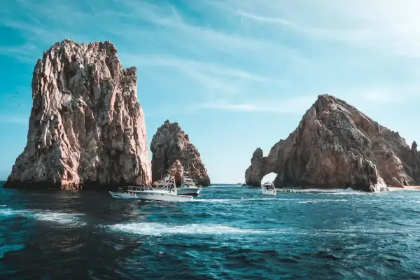 Łodzie koło skalnych formacji w Cabo San Lucas. Zastanawiasz się, ile trwa lot do Meksyku?