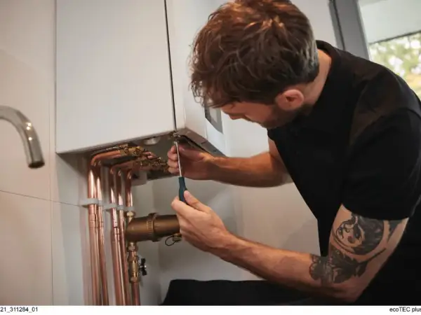 Un technicien ajuste une chaudière. Attention, trop de pression chaudière dangereux.