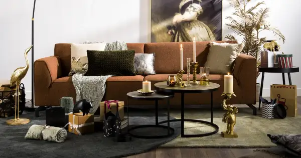 Salon chaleureux avec canapé rouille, coussins texturés et décorations dorées. L'ambiance est réconfortante, avec des touches de **couleur cooper** apportées par des bougies et des statuettes d'éléphants.