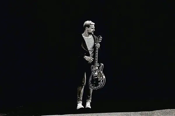 Paweł Domagała z gitarą, jakby gotowy do wykonania utworu "Weź nie pytaj".