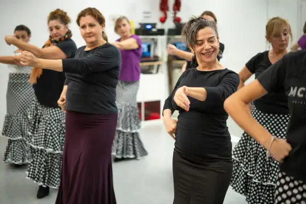 Mujeres aprendiendo como se baila el flamenco, con faldas amplias y movimientos de brazos.