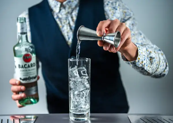 Barman nalewa Bacardi do szklanki z lodem, przygotowując klasycznego Cuba Libre.