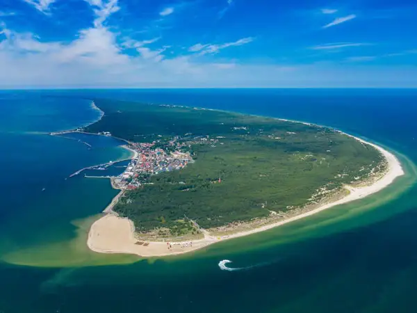Widok z lotu ptaka na Półwysep Helski, ukazujący jego imponującą długość, zalesione tereny, plaże i miasteczko z portem.