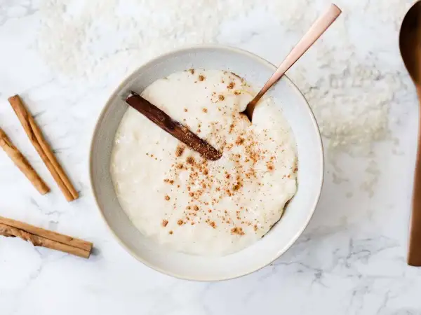 Un tazón cremoso de arroz con leche, espolvoreado con canela y una rama de canela. ¡Perfecto para aprender como hacer arroz con leche!