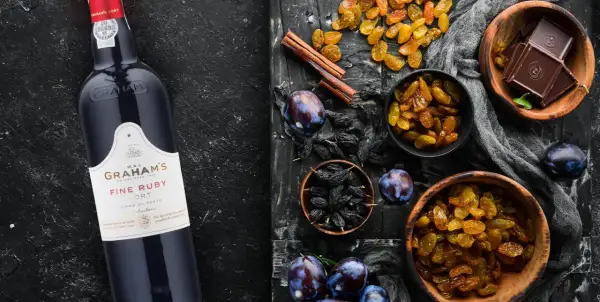 Butelka Graham's Fine Ruby Port obok bakalii: rodzynek, śliwek, czekolady i cynamonu. Idealny do deserów, porto ile procent?