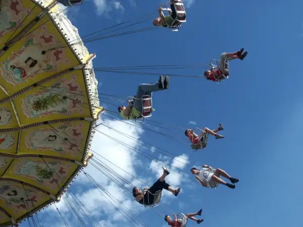 Flugkarussell auf dem Volksfest Gmund. Menschen schweben im Himmel, die bunte Kirmes dreht sich.