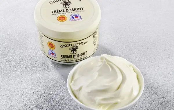 Crème d'Isigny : un pot et un bol de crème fraîche onctueuse. Parfaite pour la cuisine, sa richesse sublime vos plats.