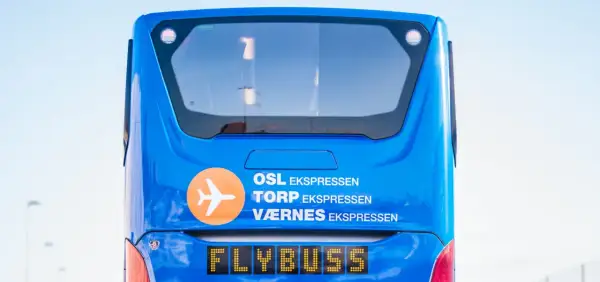 Niebieski Flybuss z napisem "OSL EKS<bos>. TORP EKS PRESEN", gotowy do podróży z lotniska Torp do centrum Oslo.