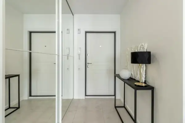Nowoczesny wiatrołap inspiracje: białe drzwi, lustrzana szafa i elegancka konsola z lampą.